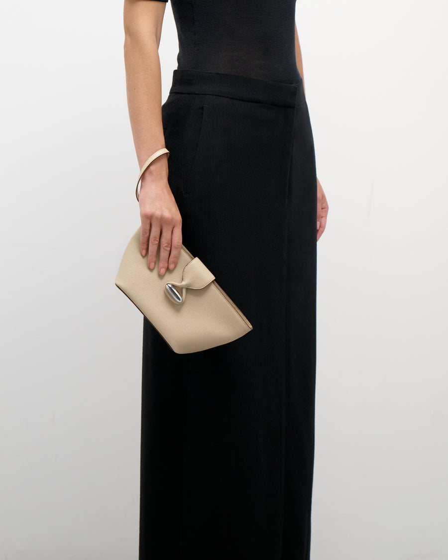 on model view of a bone beige leather pouch with silver hardware on a white background