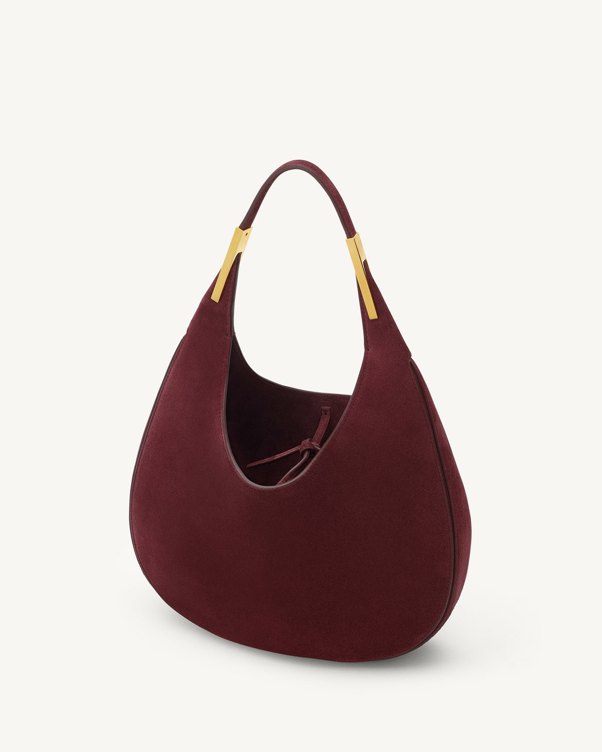 interior view of a plum red suede bag with gold hardware on a white background