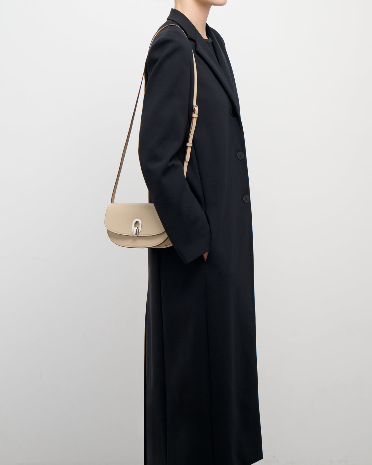 on model view of a bone beige leather bag with a silver clasp on a white background