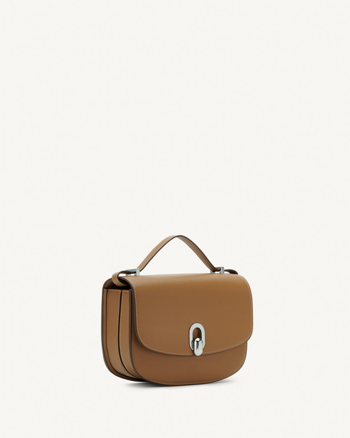 Side view of saddle leather handbag with silver hardware and a crossbody strap on a white background
