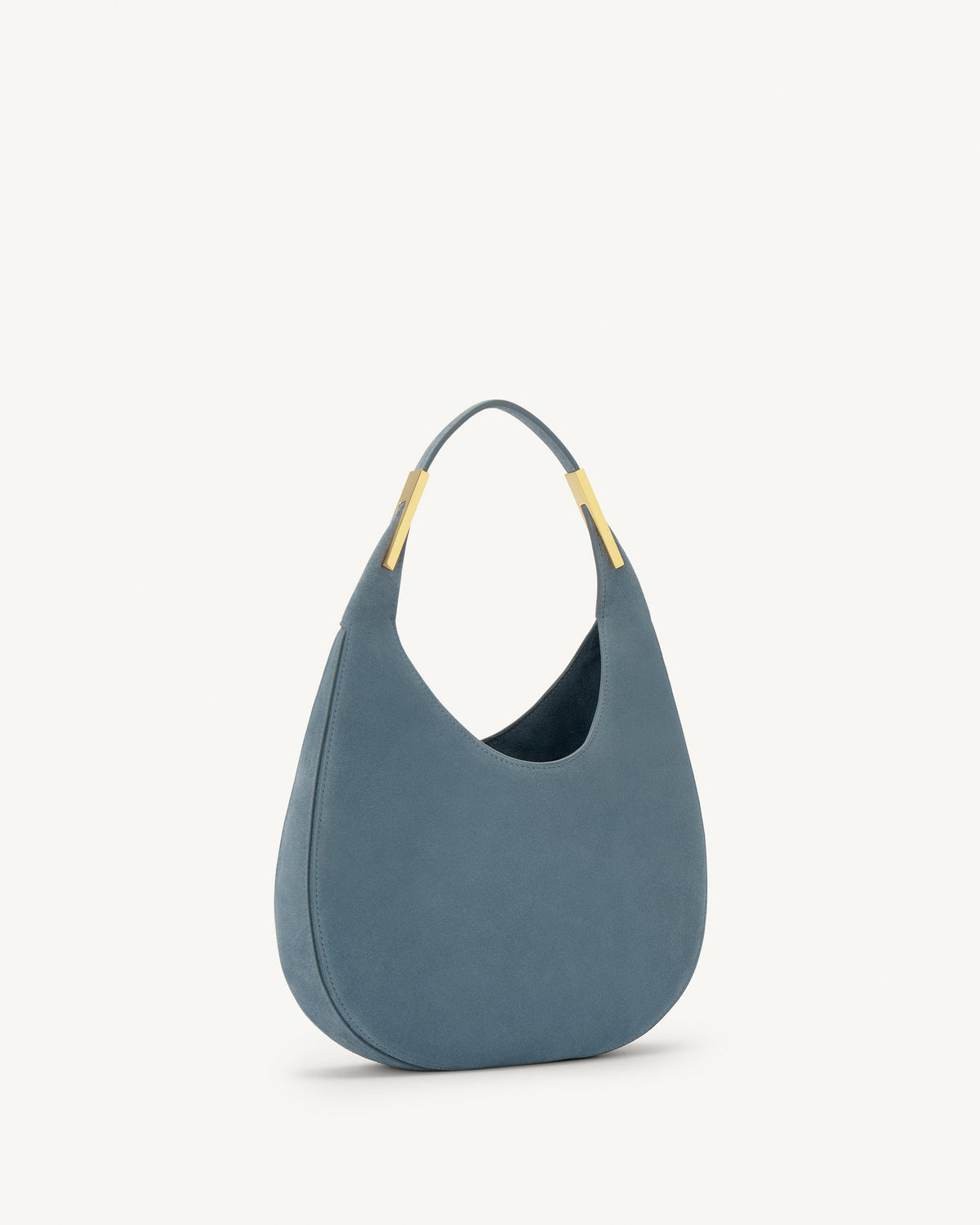 side view of a denim blue suede bag with gold hardware on a white background