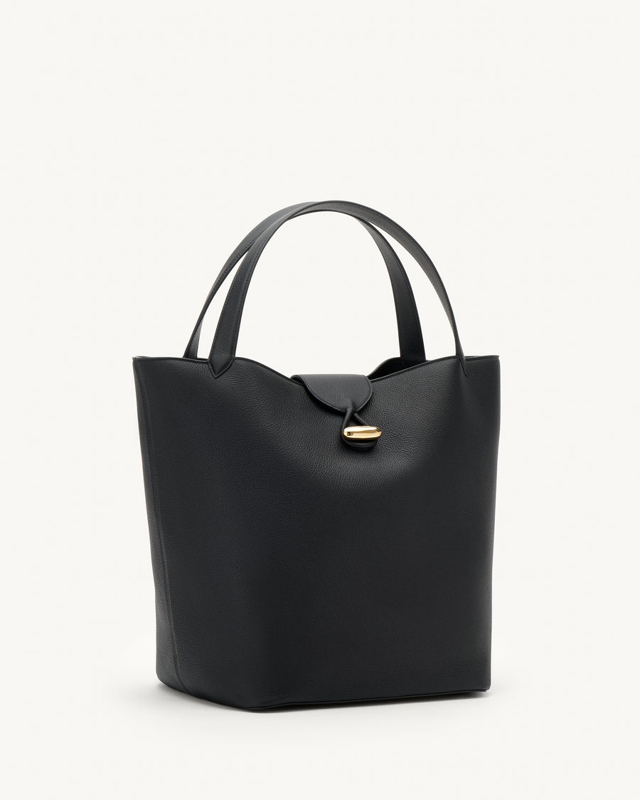 side view of a black tote bag with gold hardware on a white background