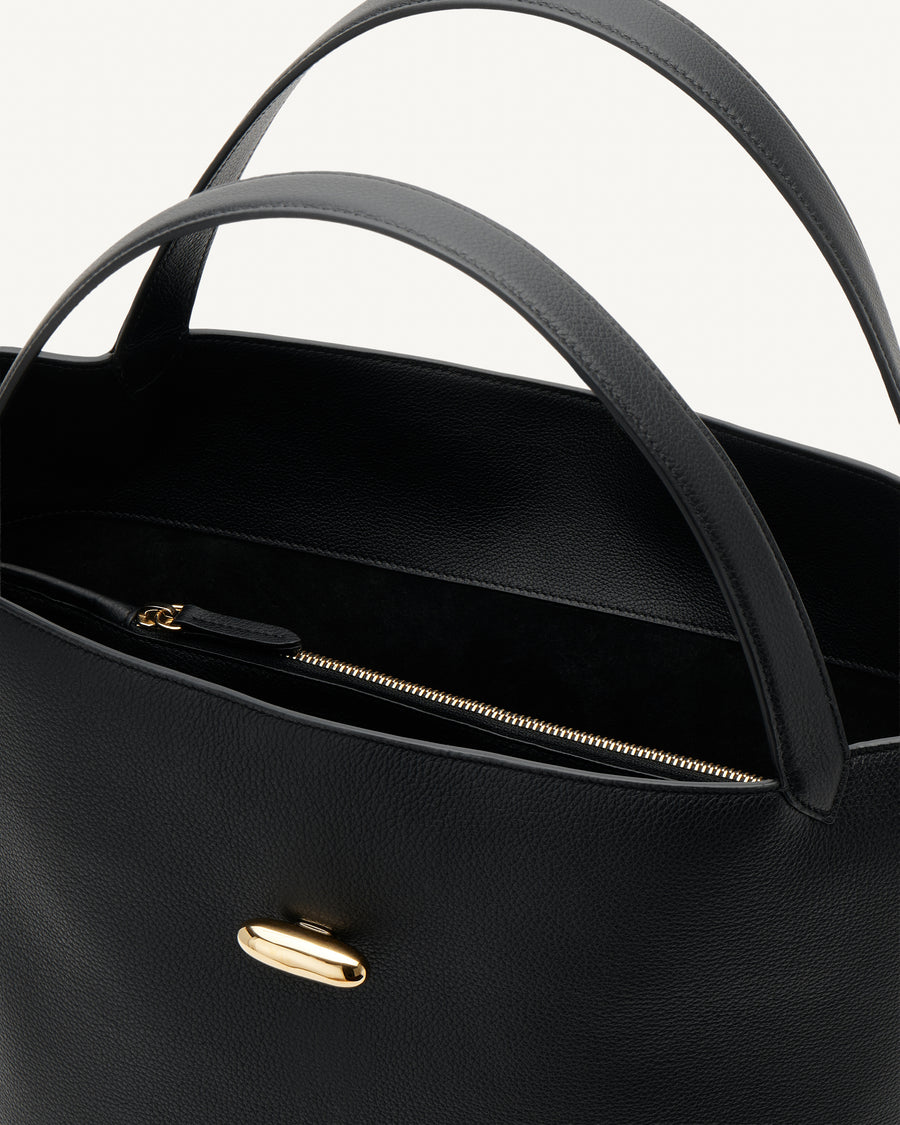 interior view of a black tote bag with gold hardware on a white background