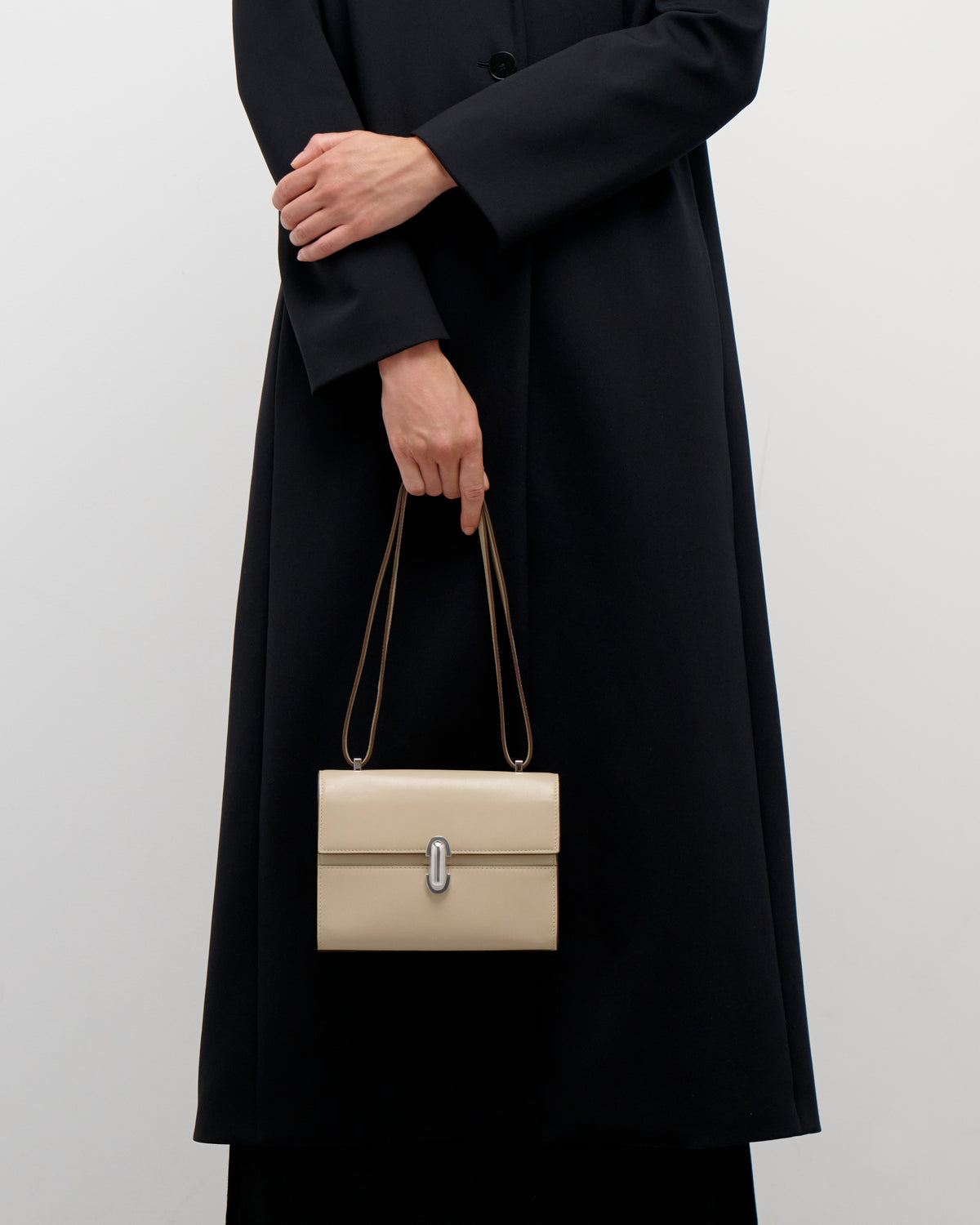 on model view of a bone beige leather bag with a silver clasp on a white background