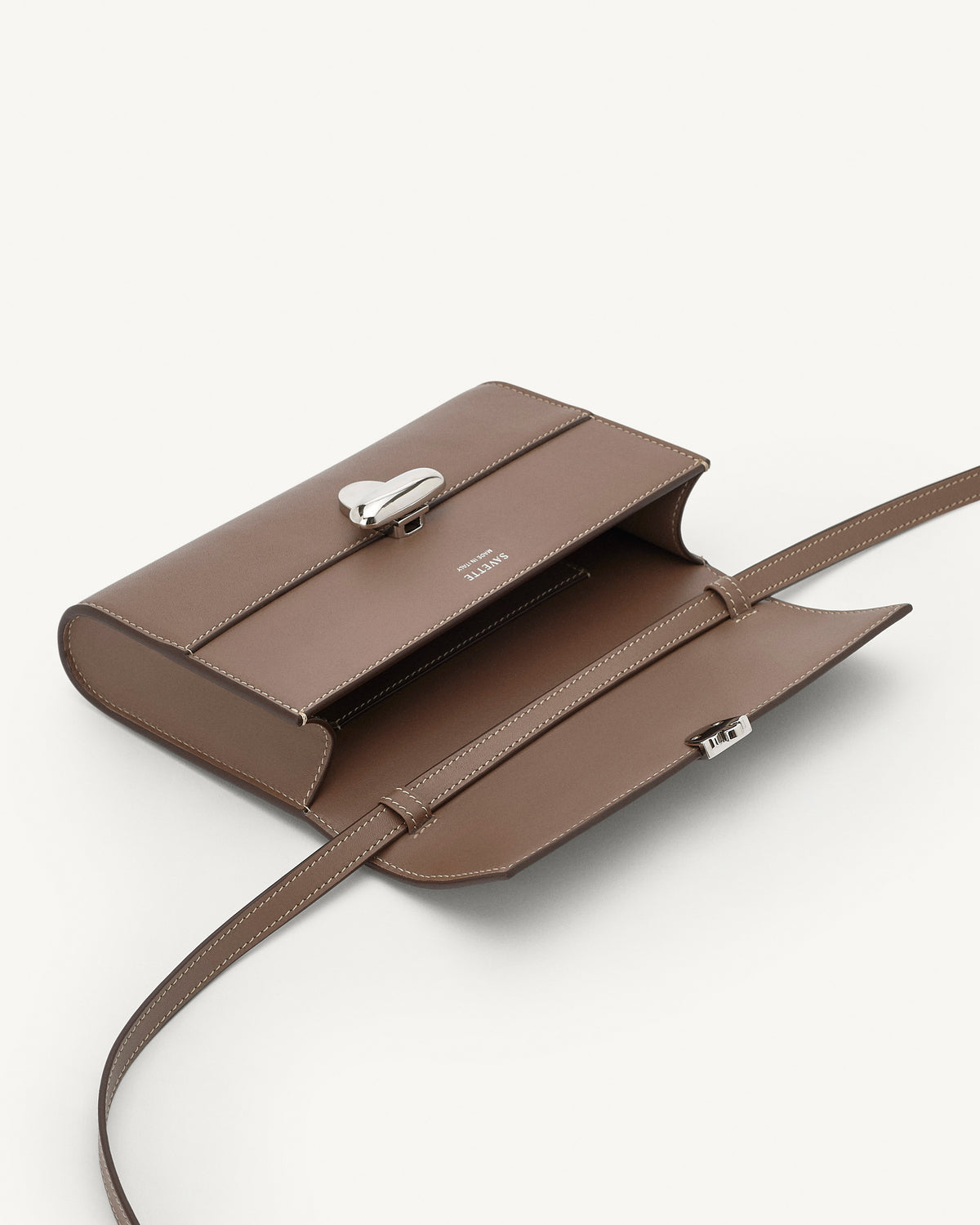 interior view of a taupe brown bag with silver clasp on a white background