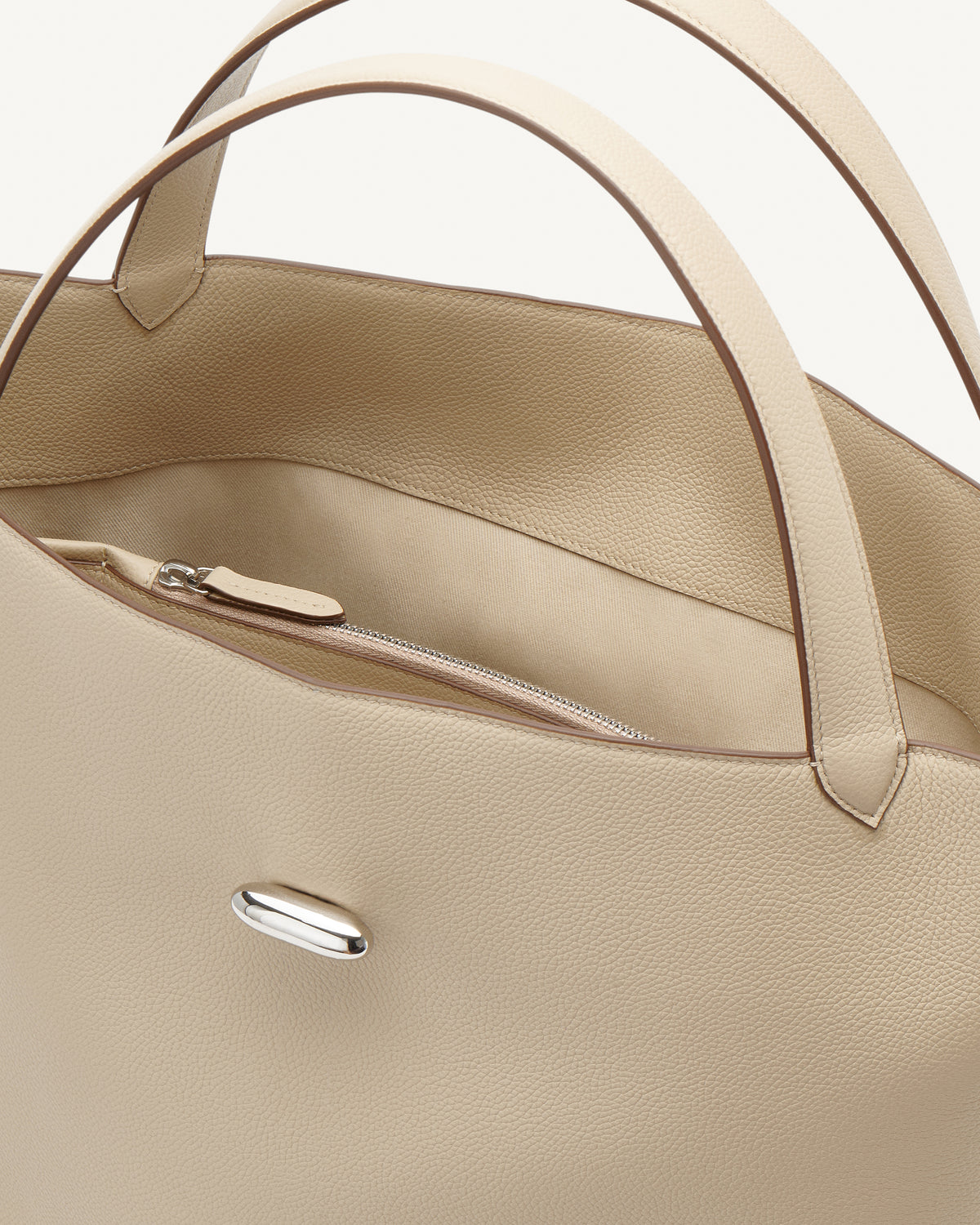 interior view of a bone beige bag with silver hardware on a white background