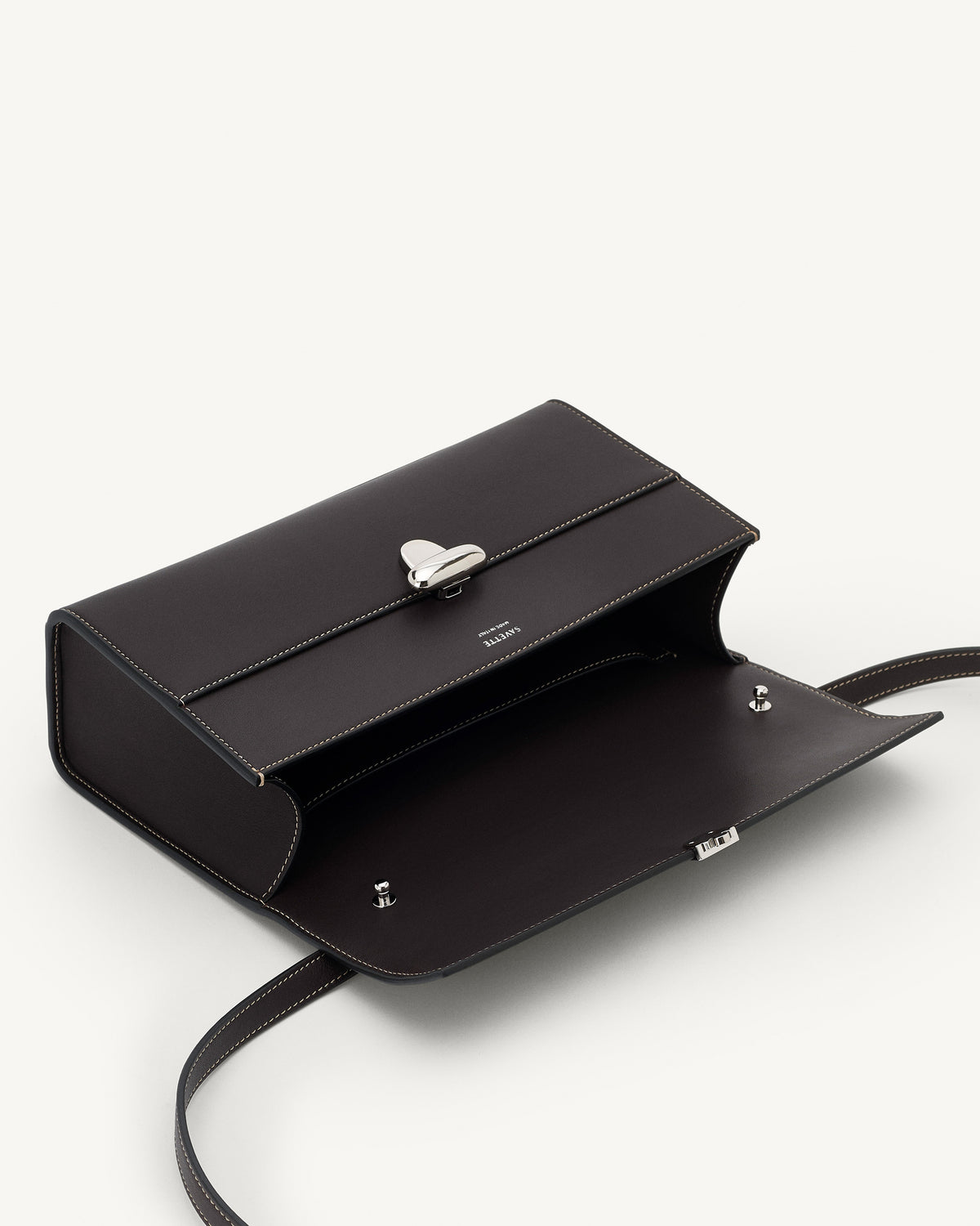 interior view of a currant brown bag with silver clasp on a white background