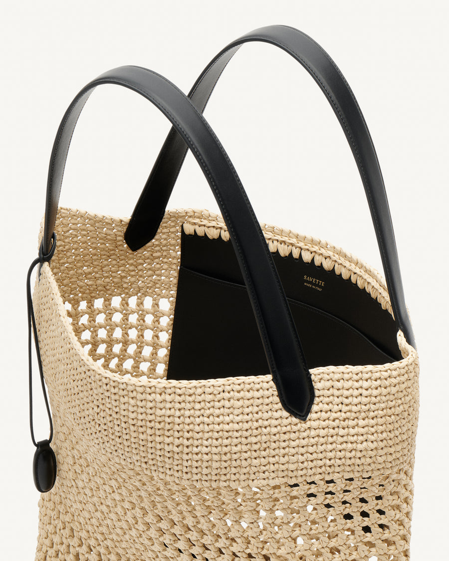 Inside view raffia tote bag with black handle on a white background