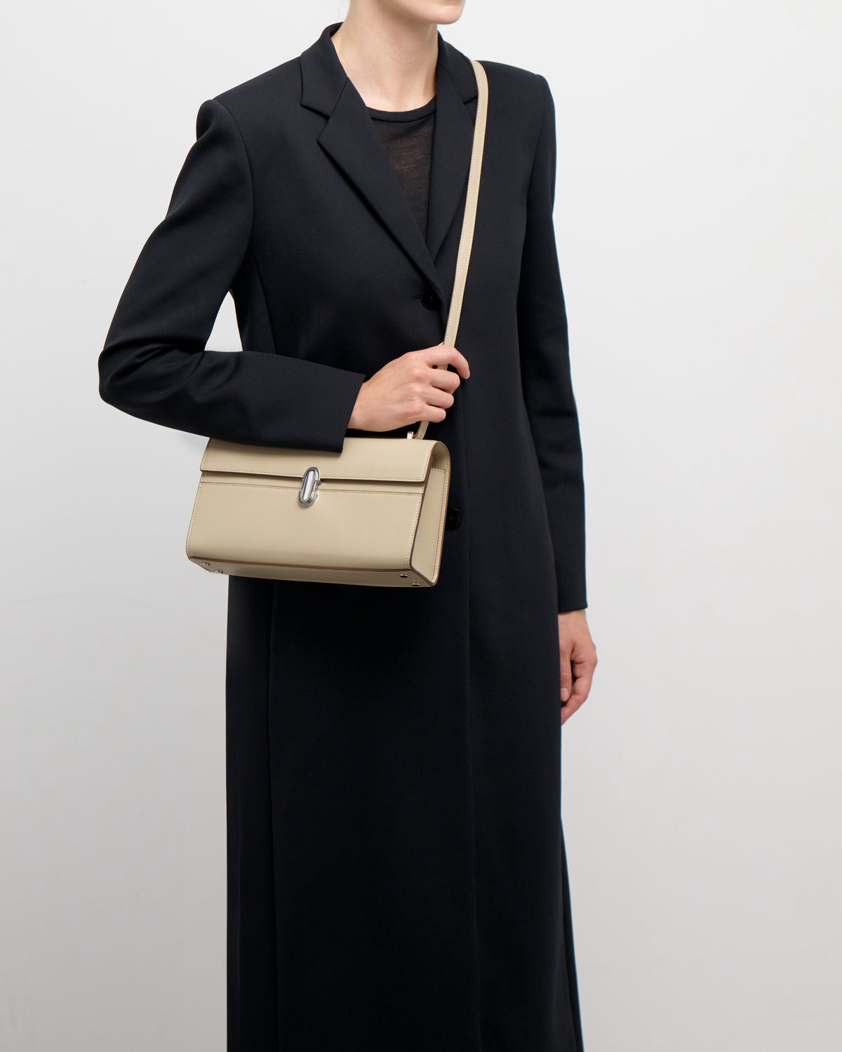 on model view of a bone beige leather bag with a silver clasp on a white background