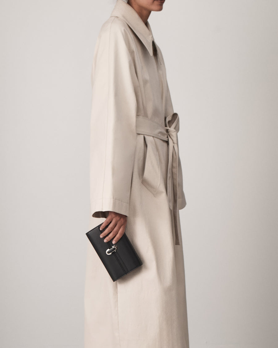 on model view of a black leather handbag with a black leather covered silver clasp on a white background 
