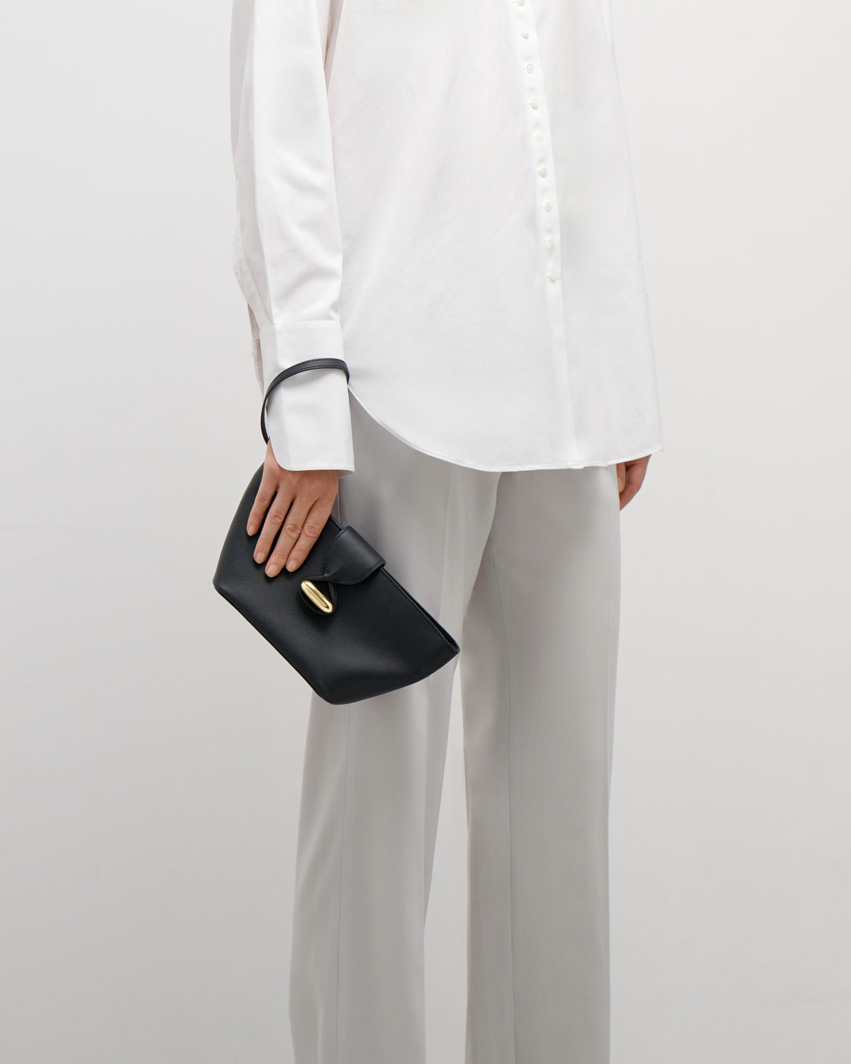 on model view of black leather pouch with gold hardware on a white background