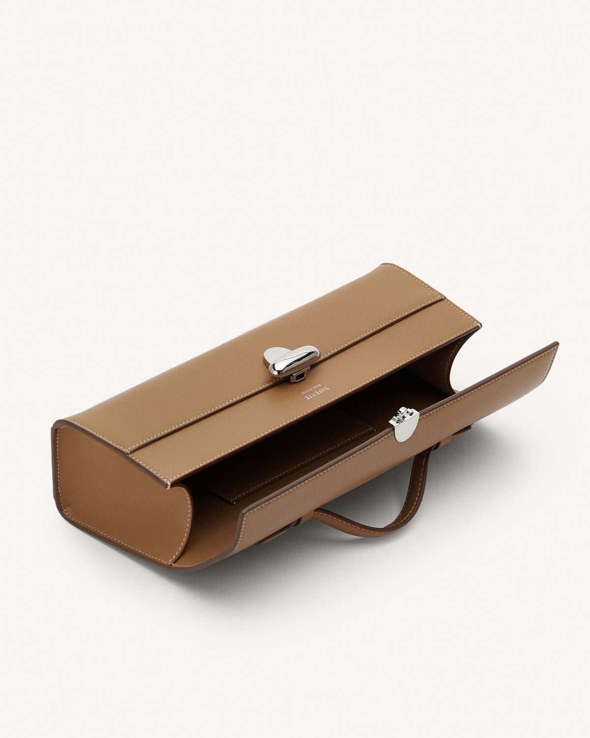 Inside view of Saddle leather handbag with a silver clasp on a white background