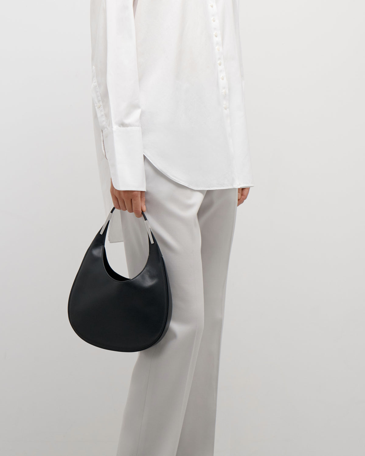 on model view of black leather bag with silver hardware on a white background