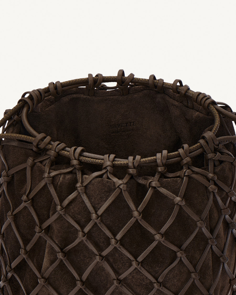 interior view of a coffee brown macrame woven clutch bag with leather drawstring and a gold hardware piece at the bottom on a white background 