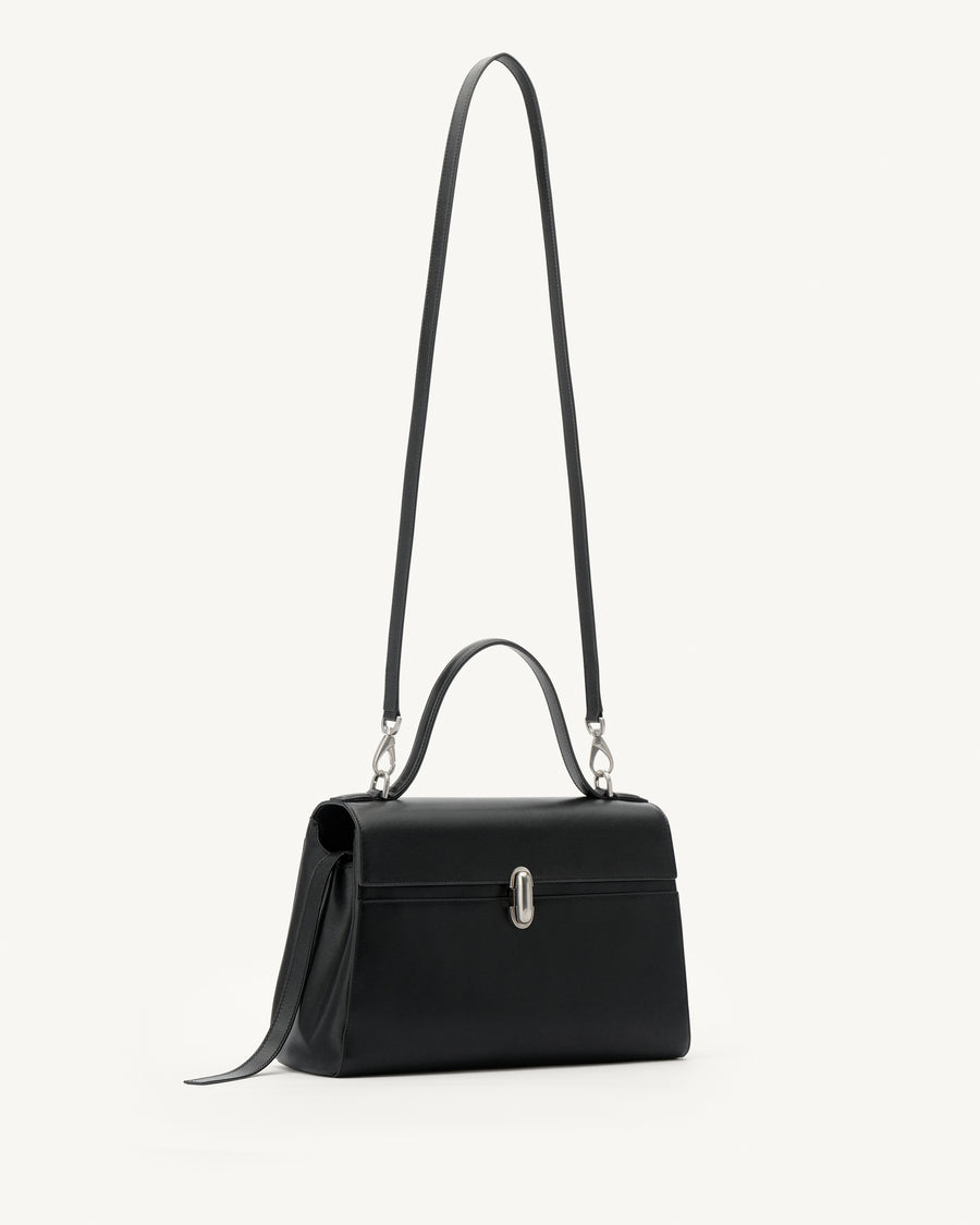 side view of a black leather handbag with a silver clasp on a white background