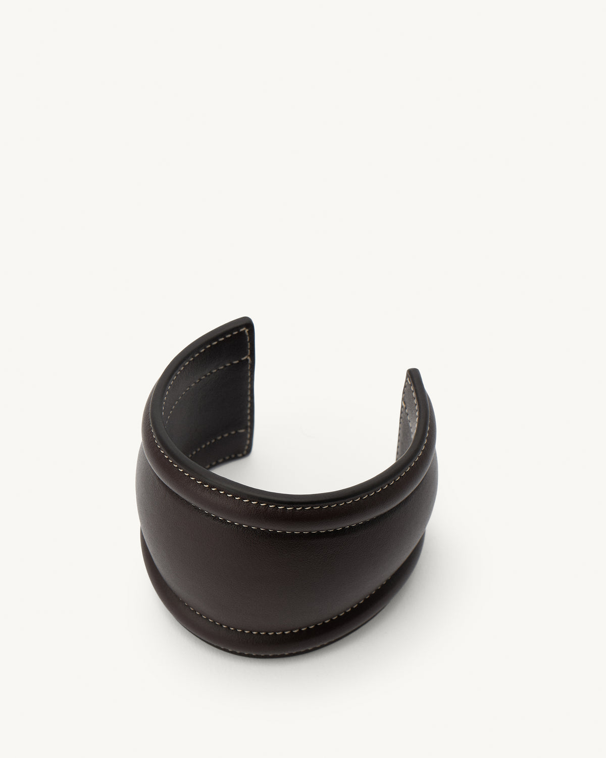 front aerial view of a coffee brown leather cuff with white stitching on a white background 