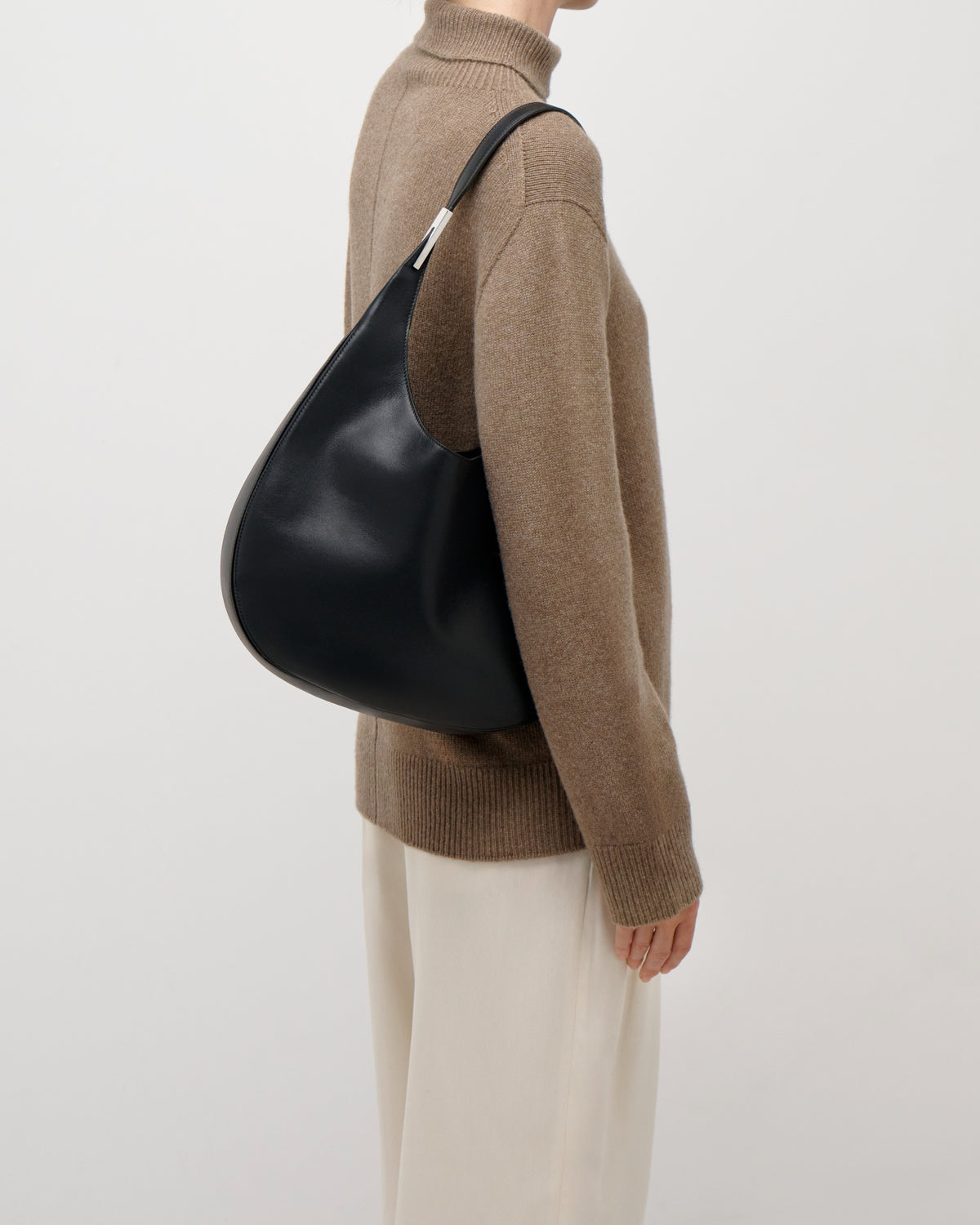 on model view of a black leather bag with silver hardware on a white background