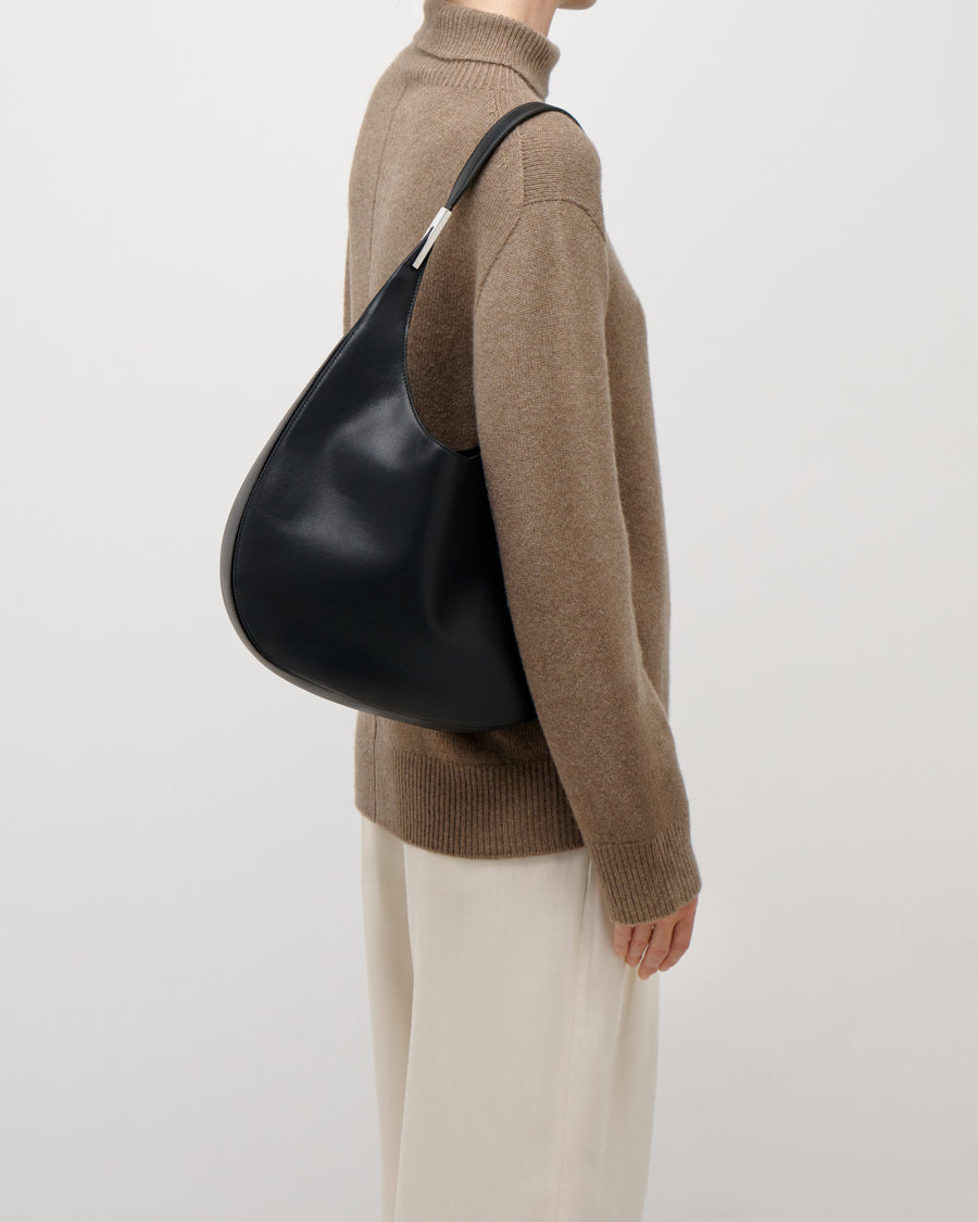 on model view of a black leather bag with silver hardware on a white background