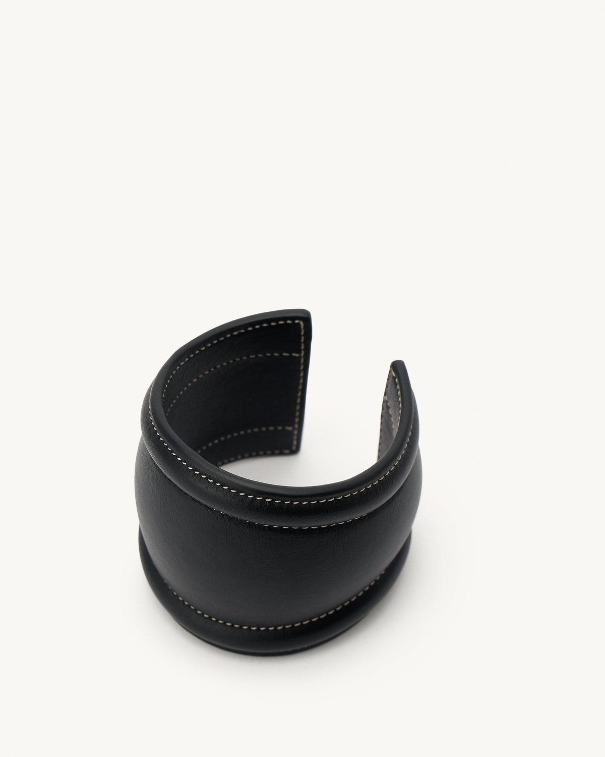 front aerial view of a black leather cuff with white stitching on a white background