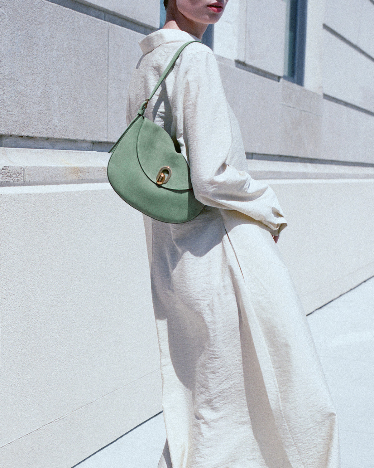 campaign on model view of a cactus green suede shoulder bag with gold hardware