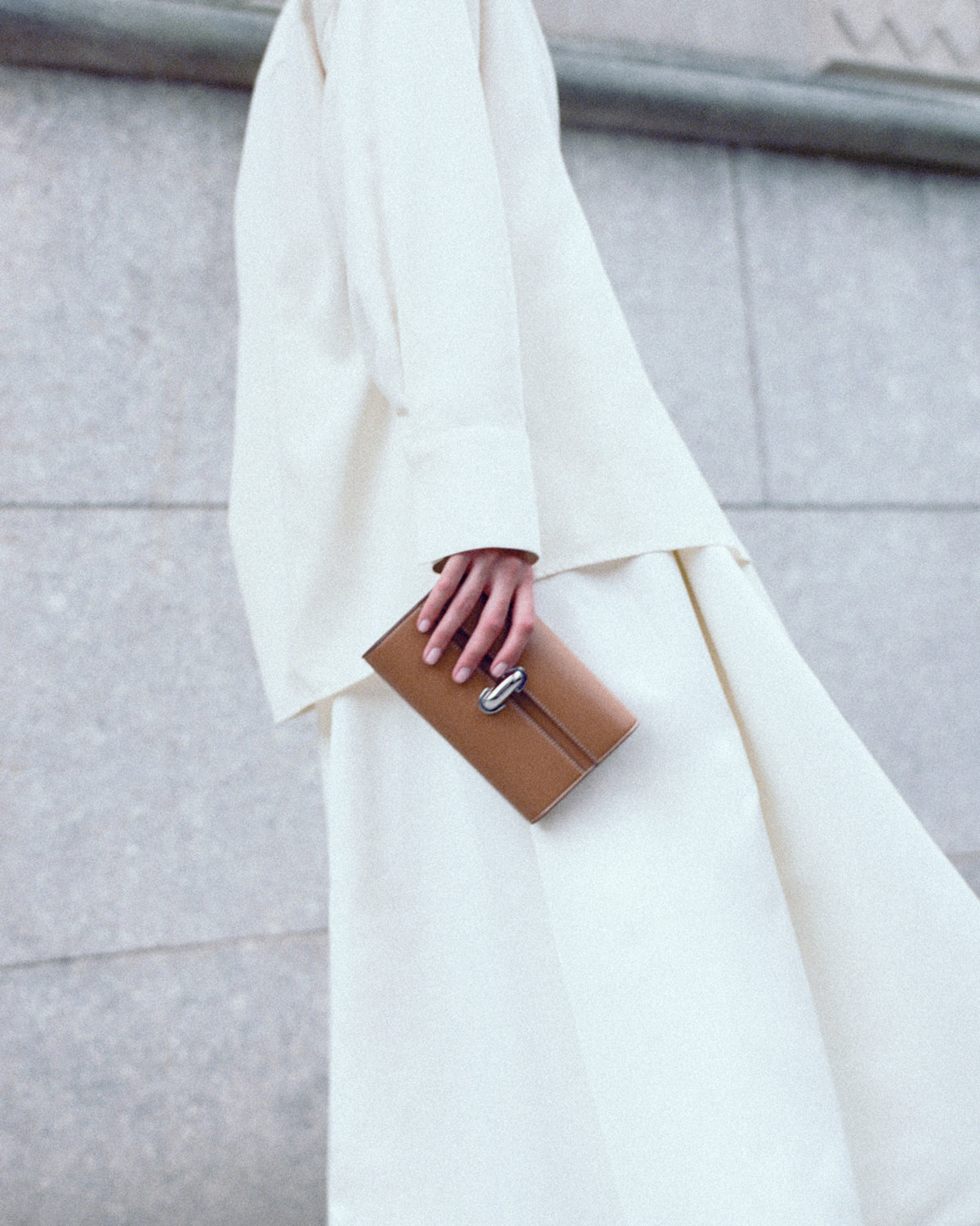 campaign on model image of a saddle brown leather clutch with silver clasp