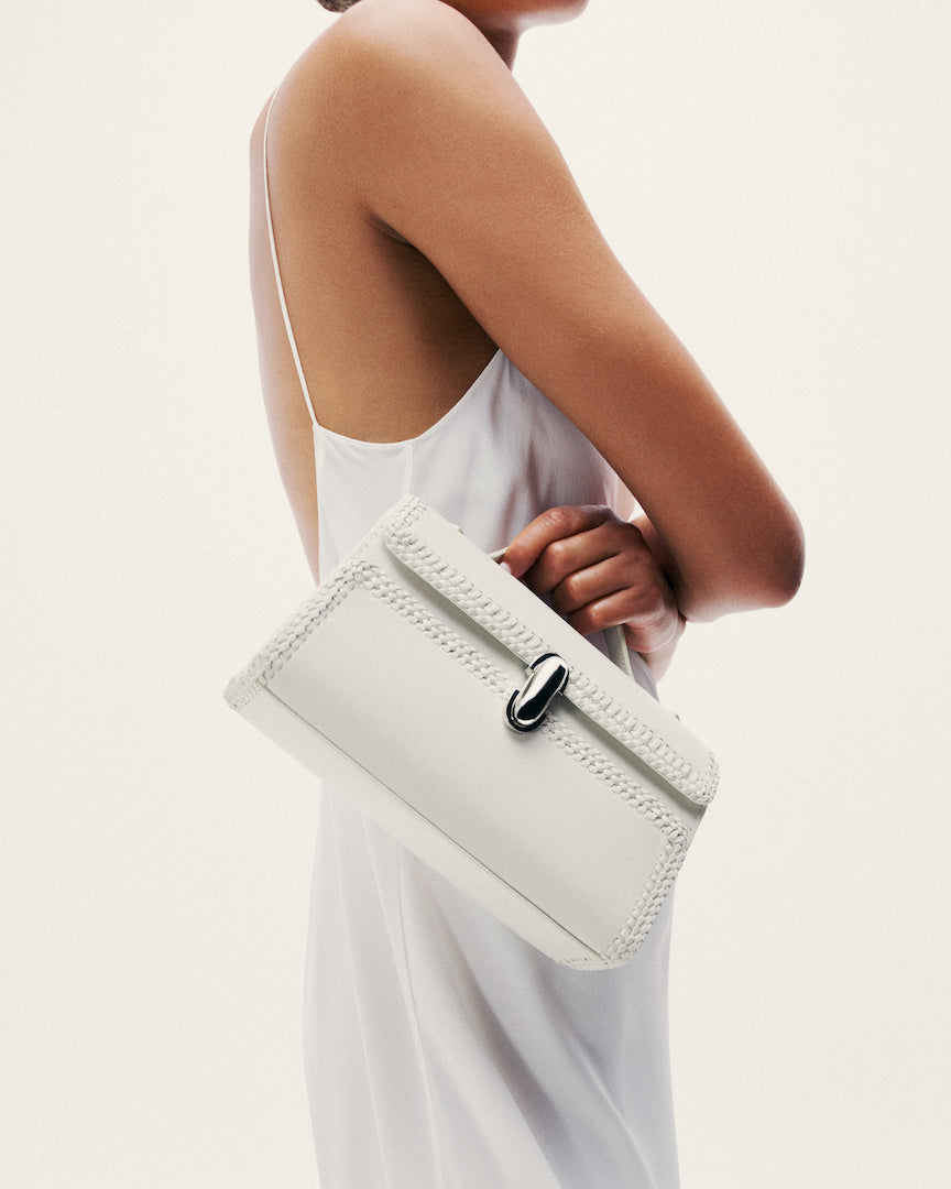 on model view of ivory white woven bag with silver clasp on a white background
