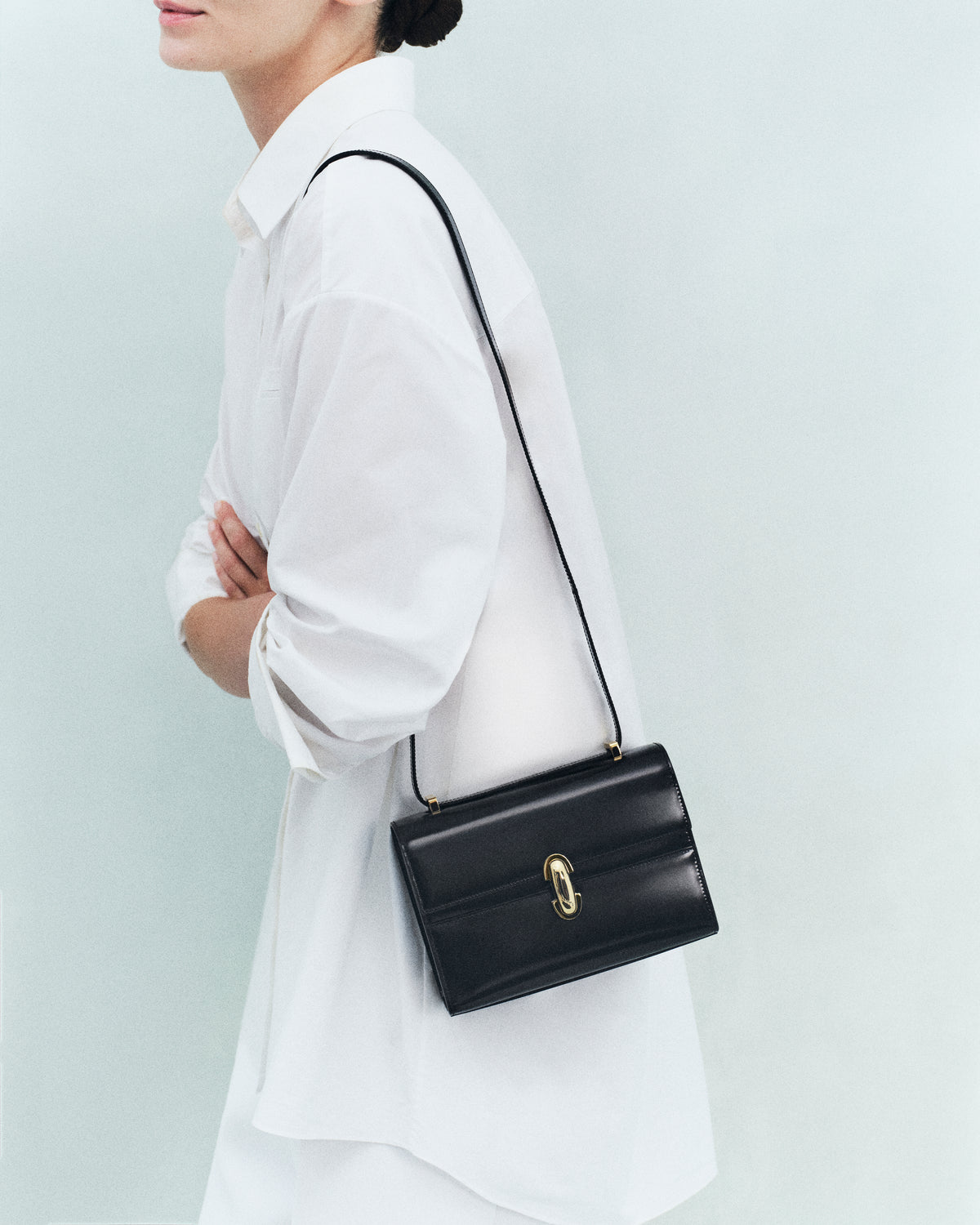 on model image of black bag with gold hardware on an off white background