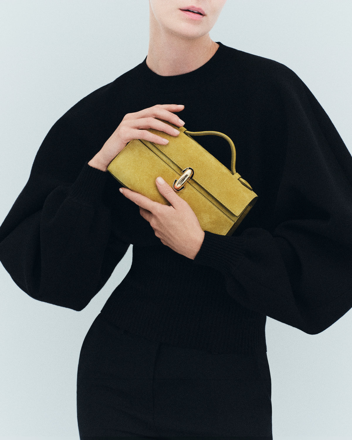 on model image of a chartreuse green suede bag with a gold clasp on an off white background