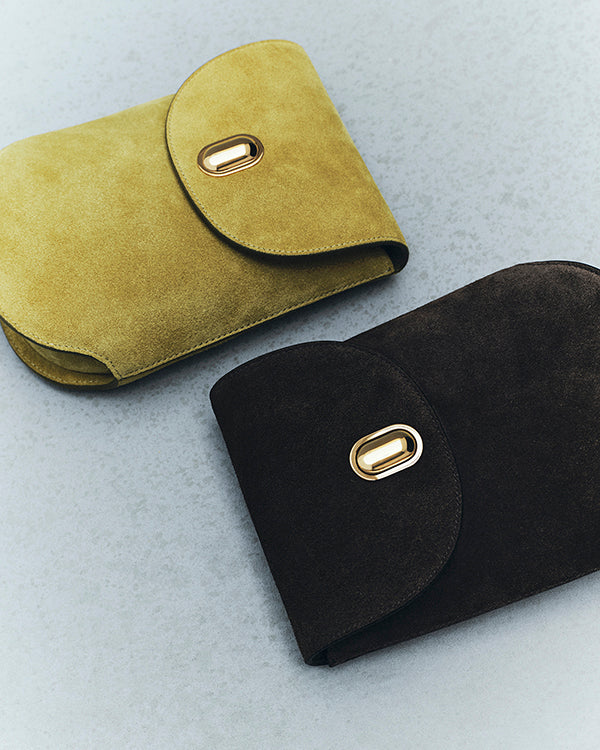 editorial image of chartreuse green bag with gold hardware and brown suede bag with gold hardware on an off white background