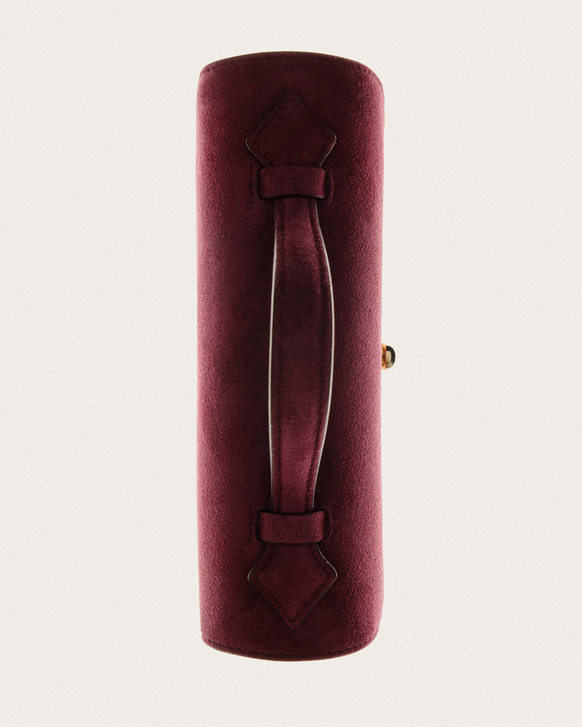 campaign aerial view of a wine red suede bag with a gold clasp on a white background