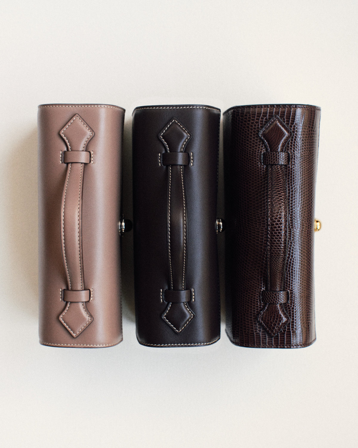campaign aerial view of a taupe brown leather bag, currant brown leather bag, and currant brown lizard bag on a white background