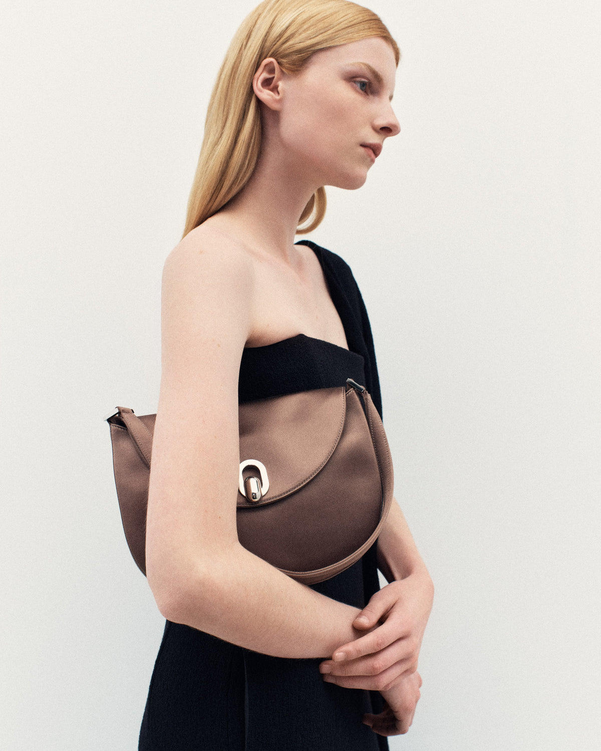 campaign on model image of taupe brown satin bag with silver hardware on a white background