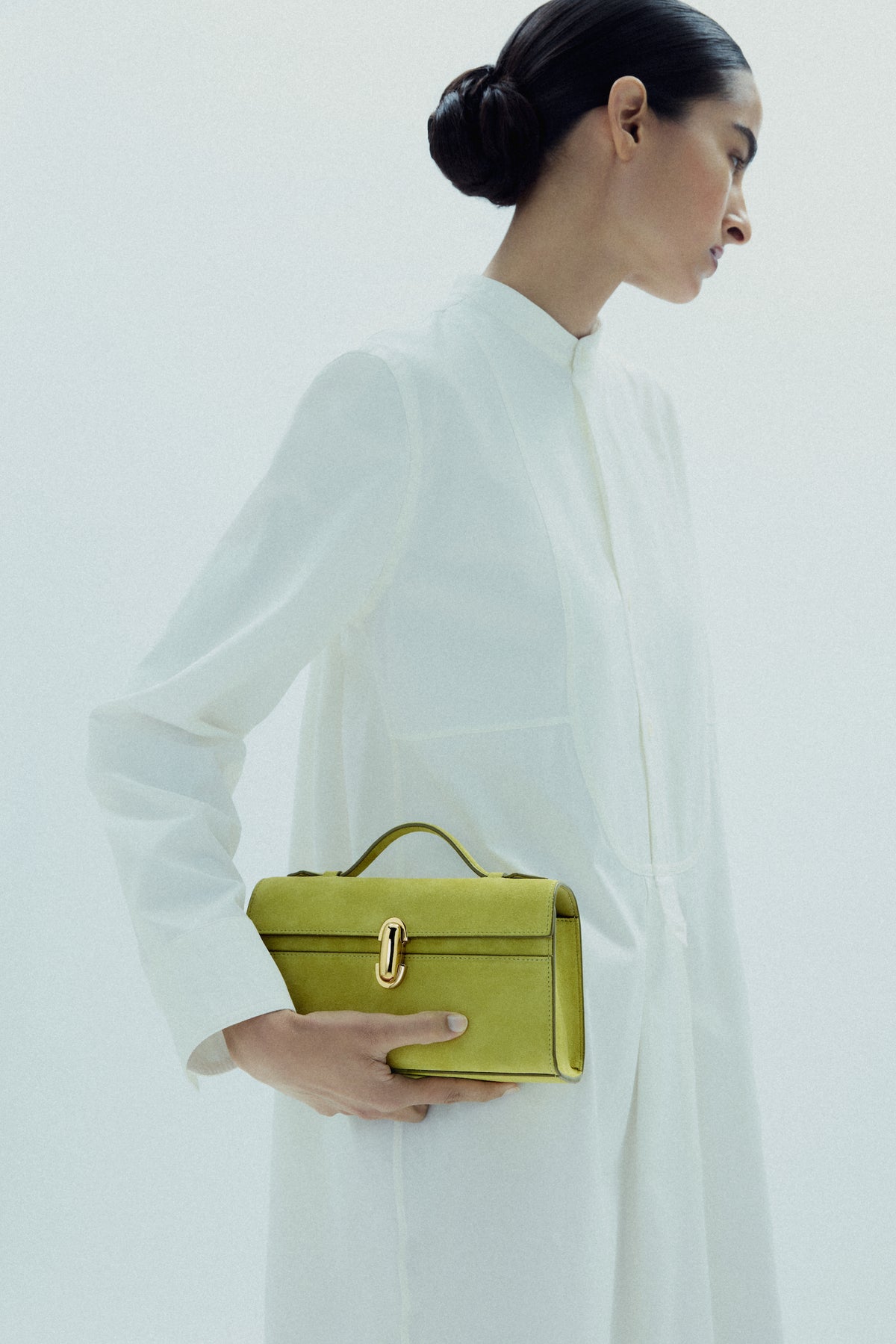 on model image of a chartreuse green suede bag with a gold clasp on a white background