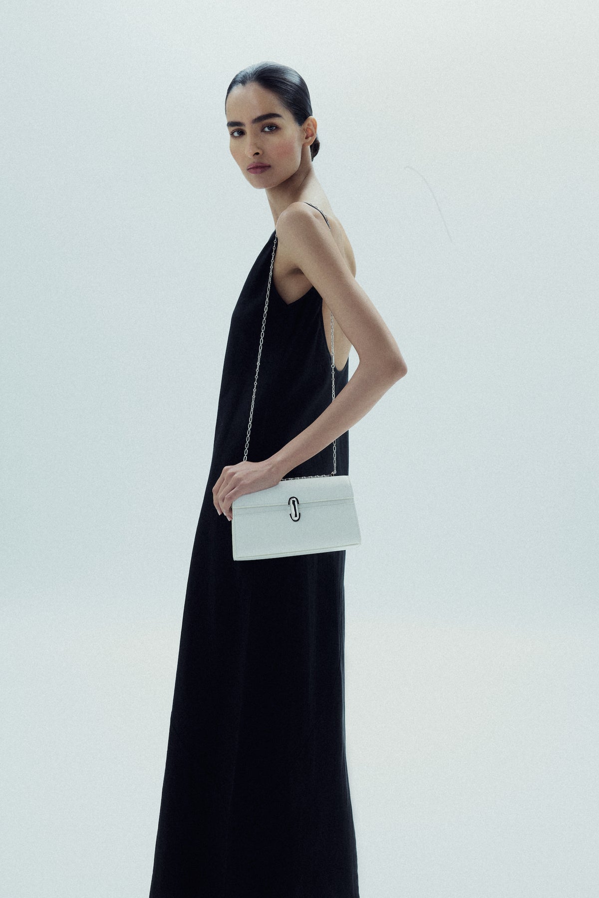 on model image of an ivory leather bag with silver clasp and silver chain on a white background
