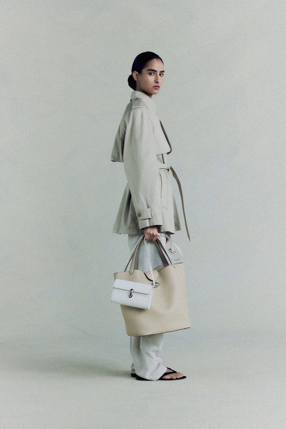 campaign on model image of a bone beige leather tote with silver hardware and an ivory bag with a silver clasp on an off white background