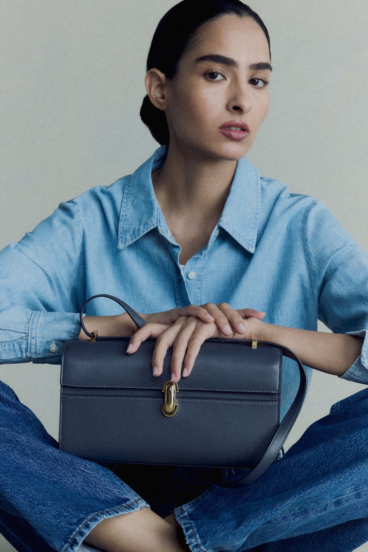 campaign on model image of a storm blue leather bag with a gold clasp