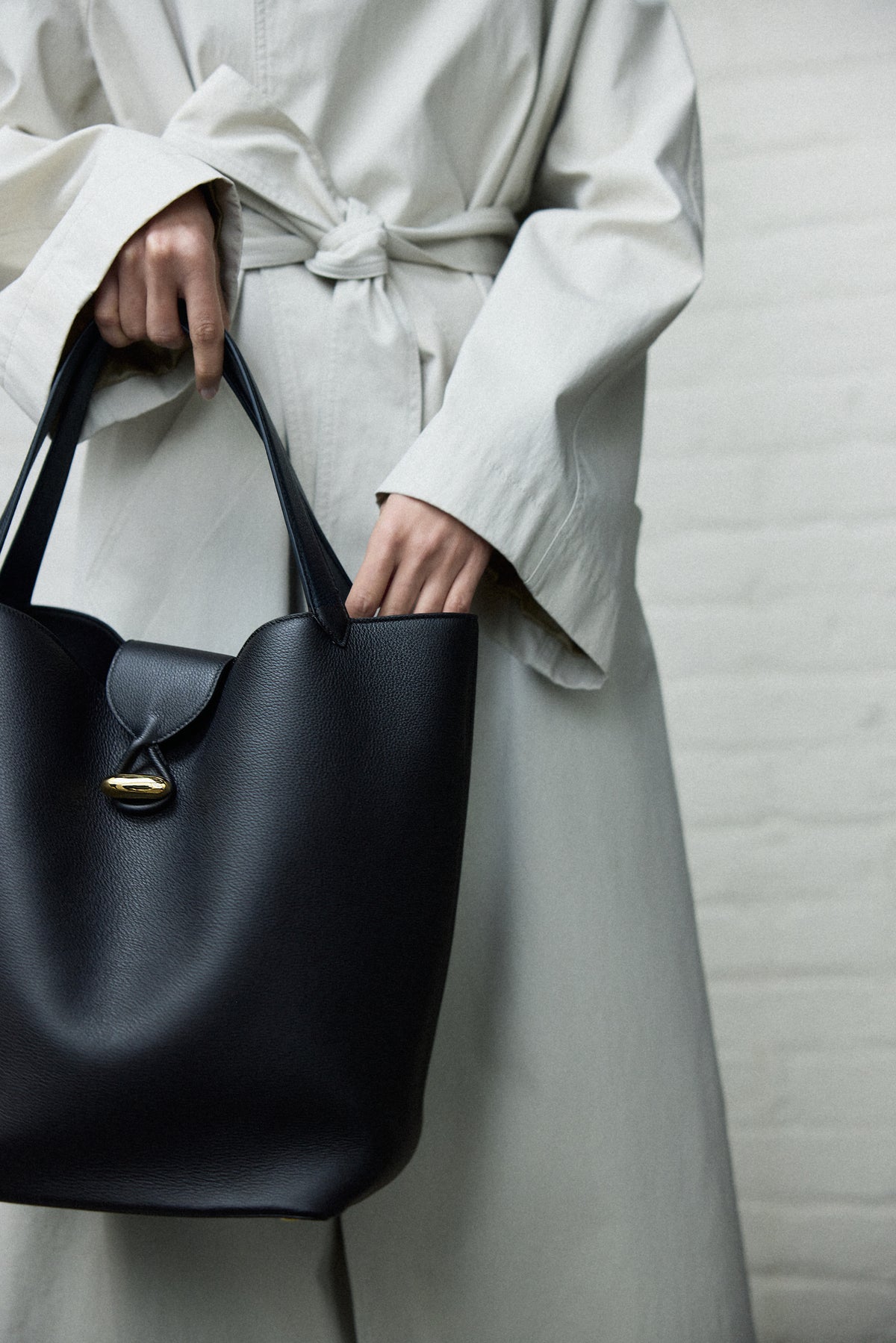 campaign on model image of a black leather tote with gold hardware