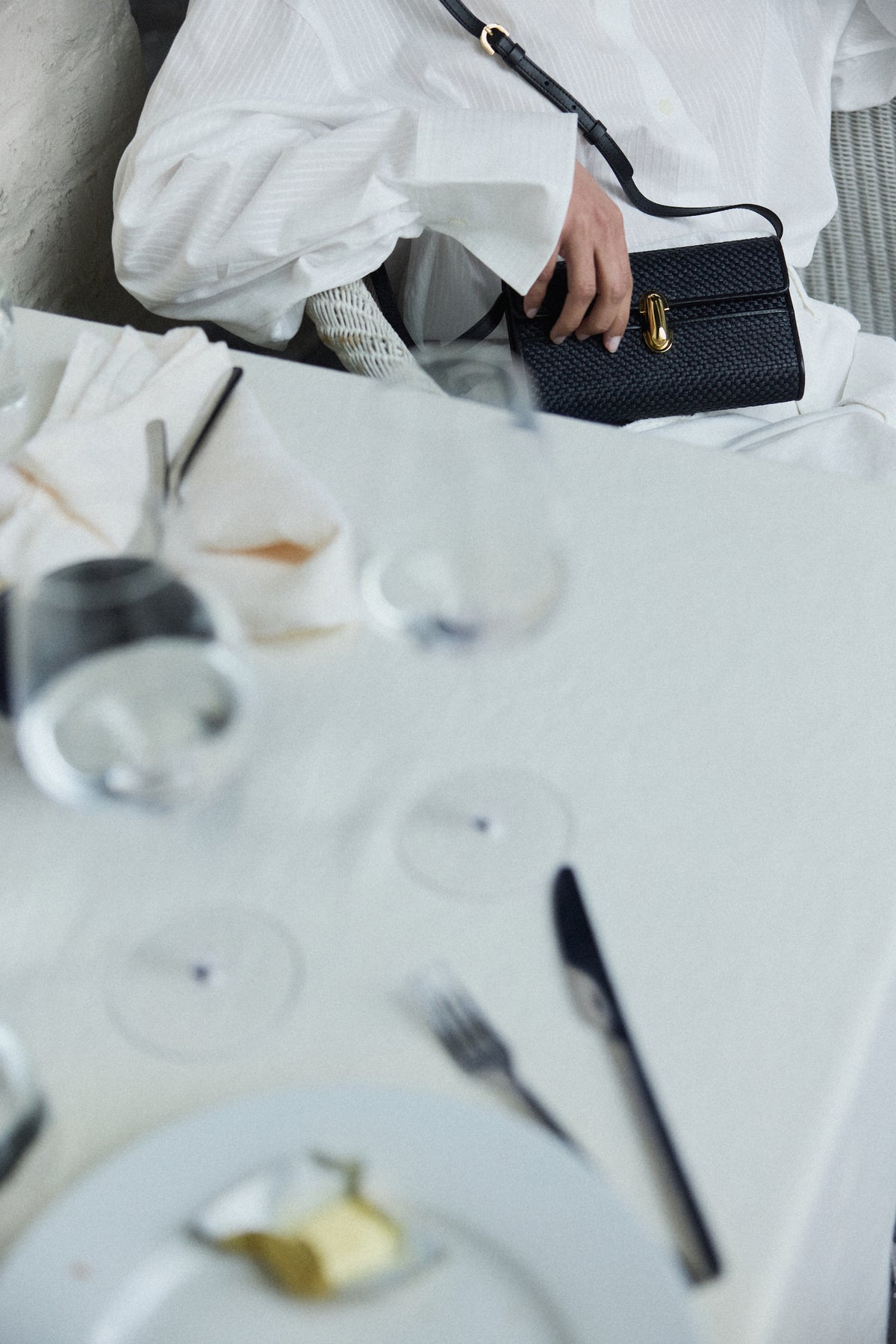 campaign image of a black raffia bag with leather trim with gold clasp
