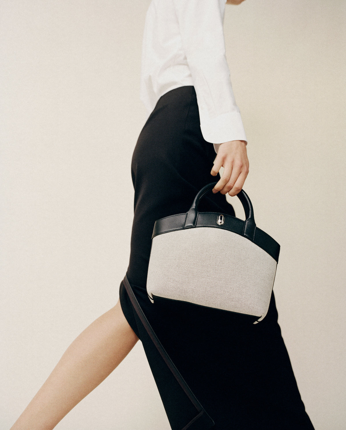 on model image of grey canvas tote with black trim and silver hardware on a white background