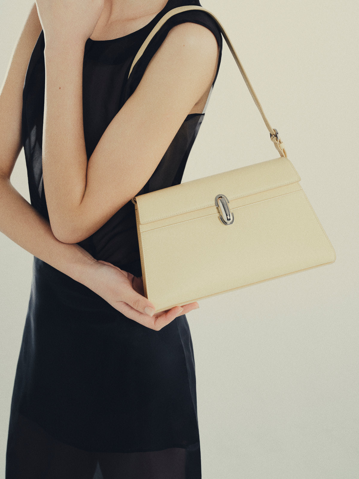 Woman holding ecru Symmetry Shoulder Bag handbag
