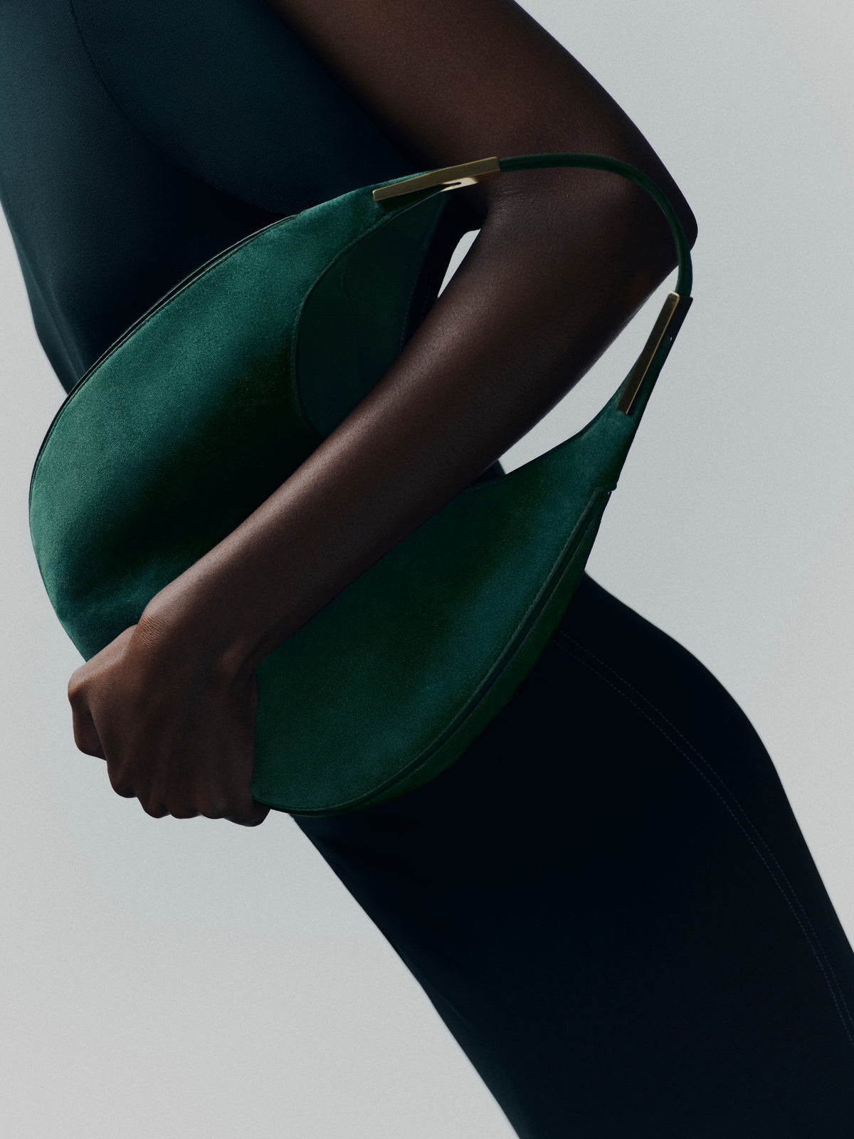 campaign on model image of pine green suede bag with gold hardware  on a white background
