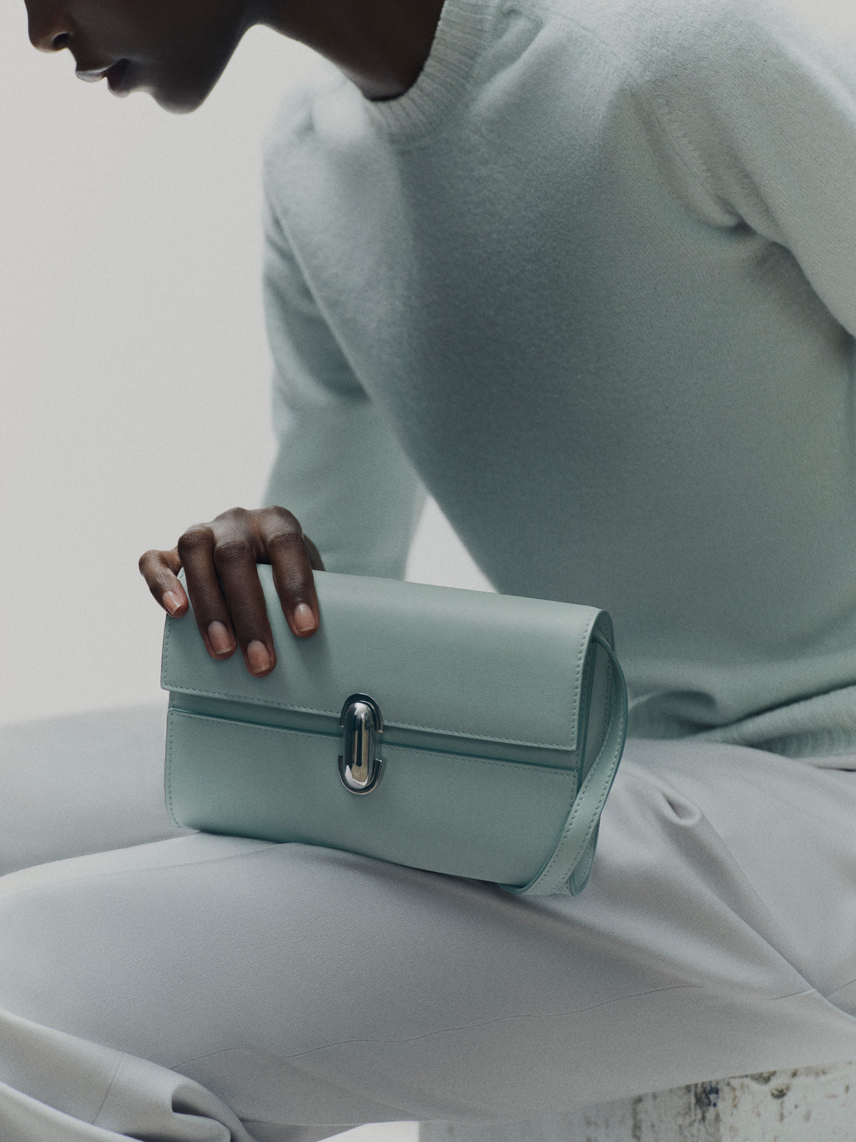 campaign on model image of mist green bag with silver clasp on a white background