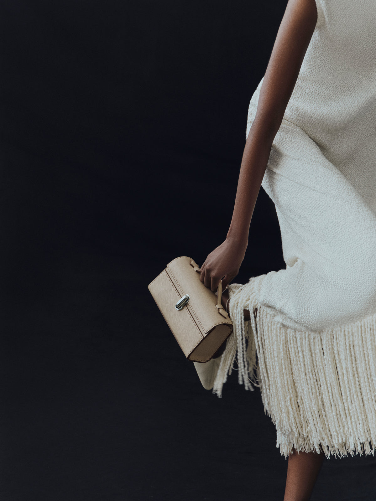 campaign on model image of bone beige bag with hand stitching and silver clasp on a black background
