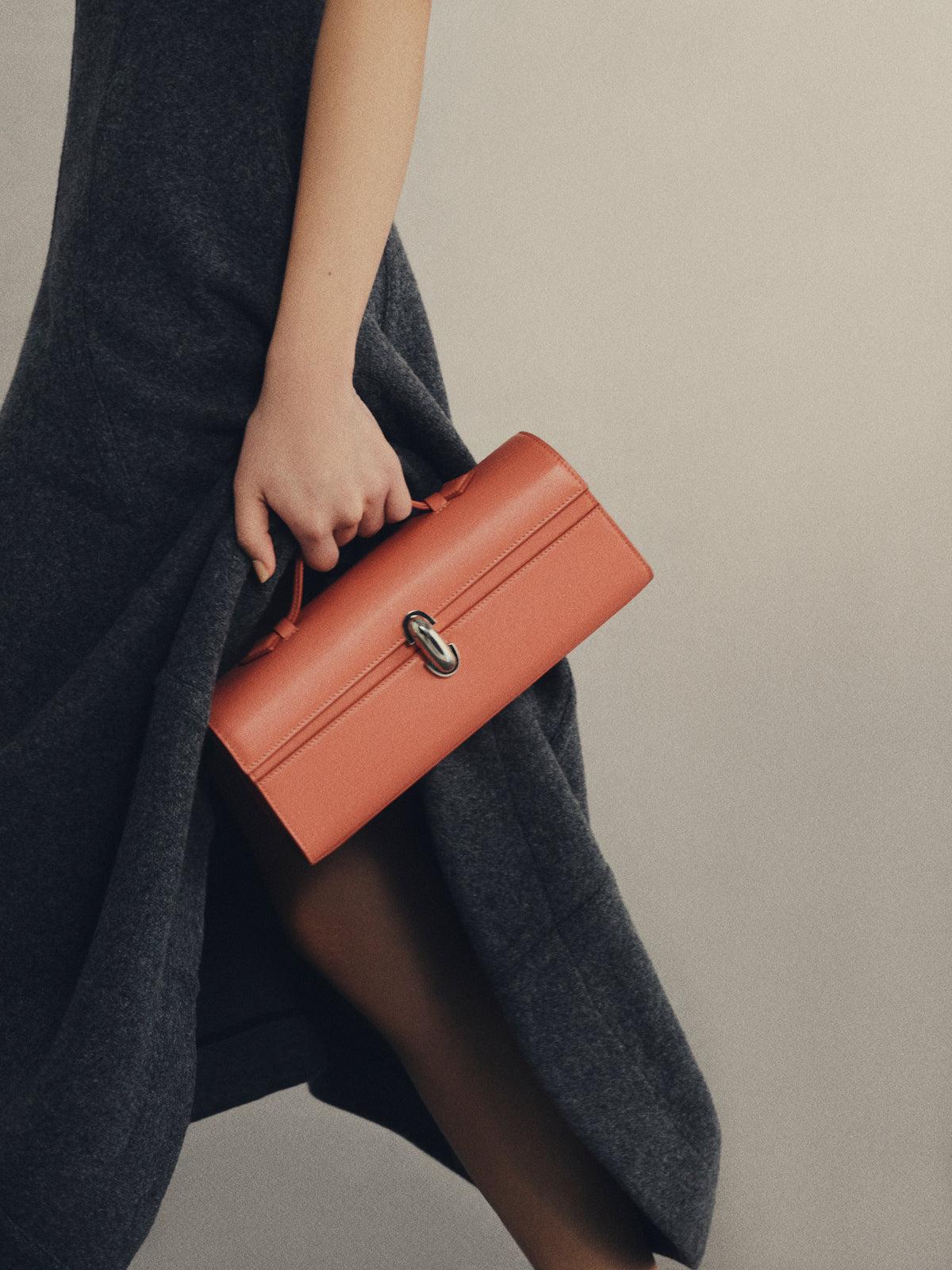 Woman walking holding pink Slim Symmetry Pochette handbag