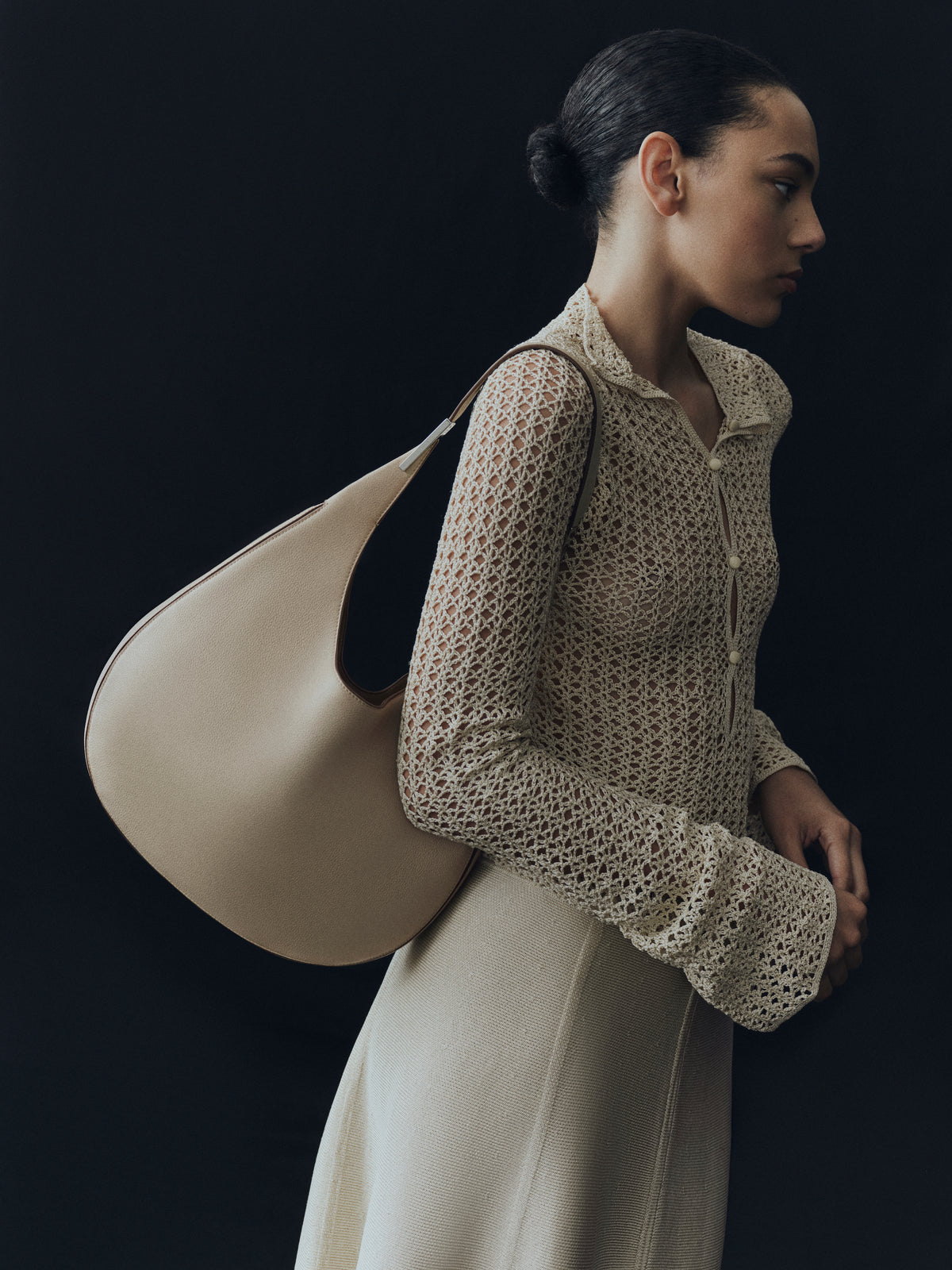 campaign on model image of bone beige bag with silver hardware on a black background