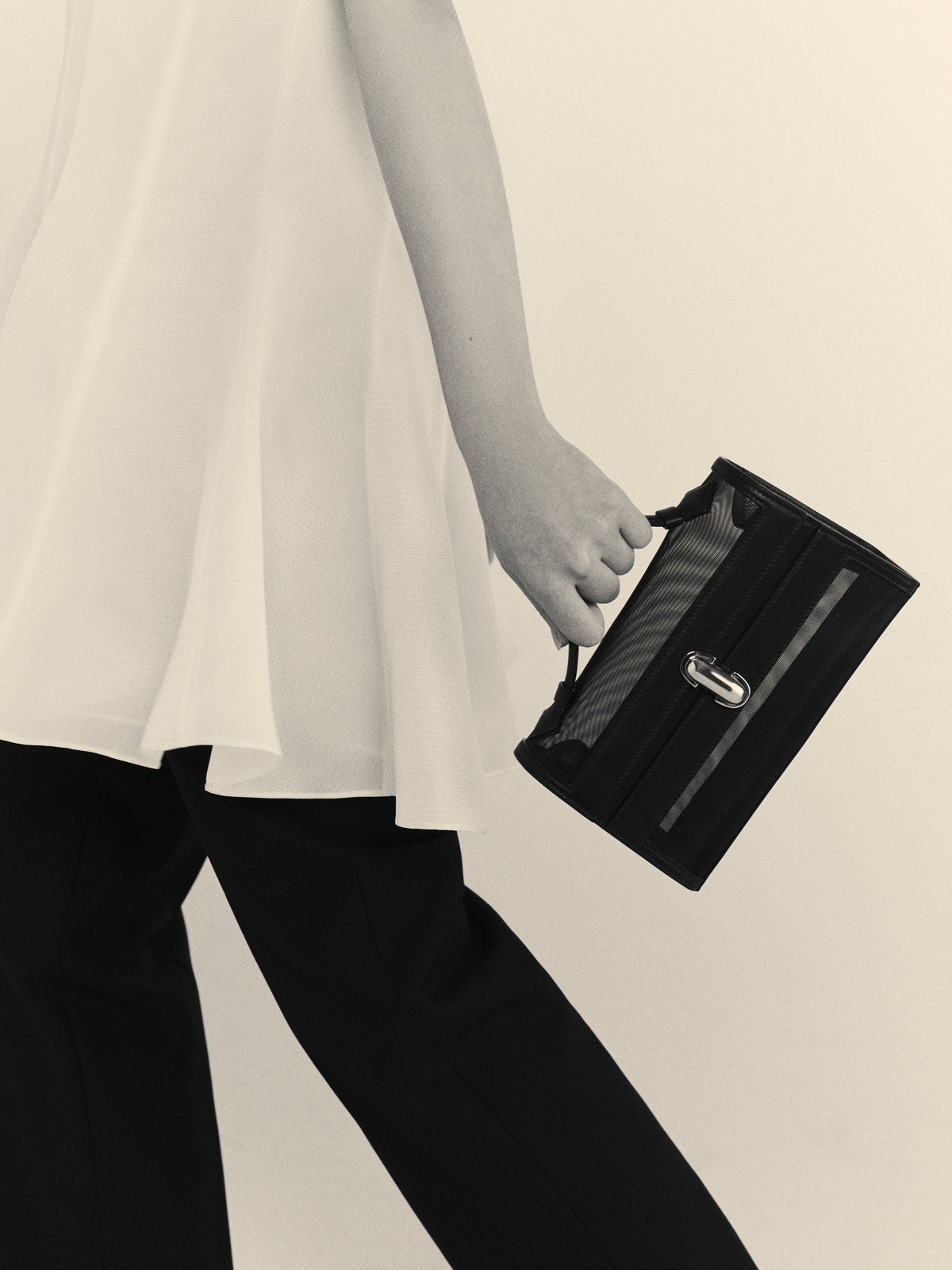 on model image of black mesh bag with leather trim and silver clasp on a white background
