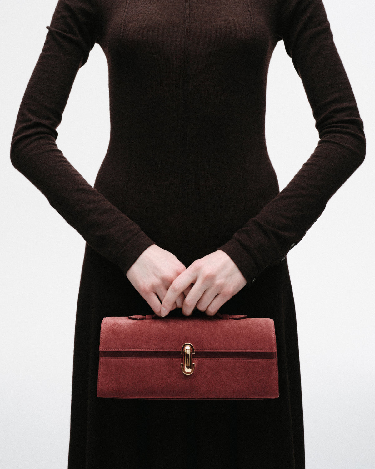 on model image of a red suede bag with a gold clasp on a white background