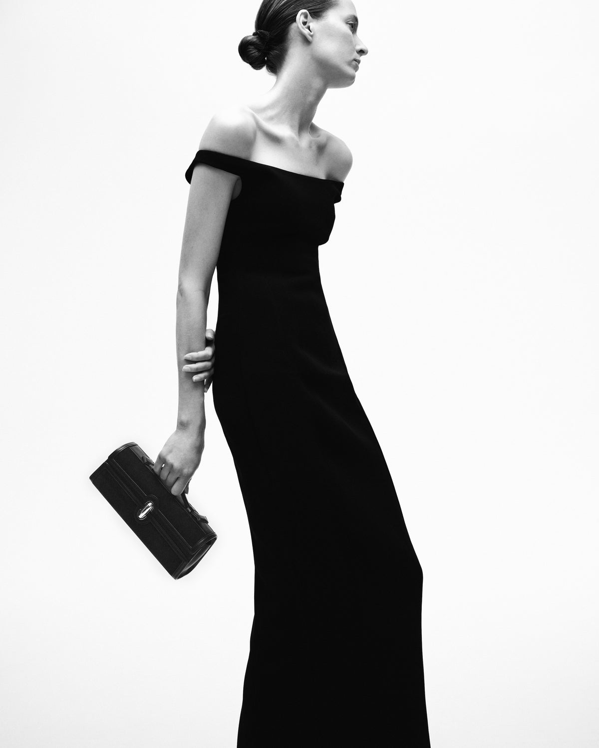 black and white editorial image of model holding a leather bag on a white background