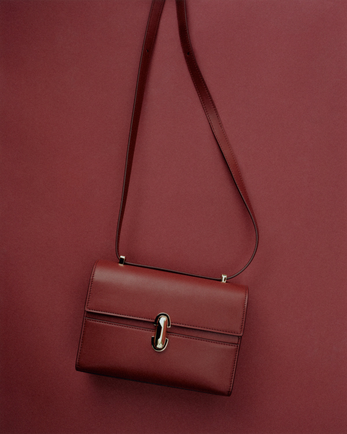 editorial image of a red bag with a gold clasp on a red background