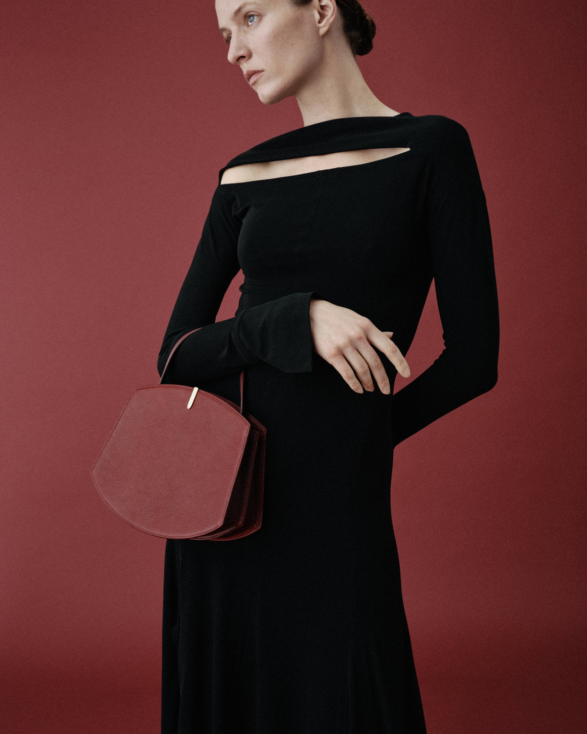 on model image of a red bag with a gold clasp on a red background